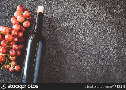 Bottle of red wine with bunch of grapes flat lay