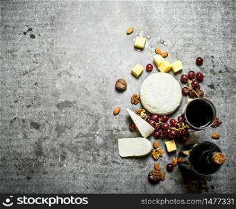 Bottle of red wine with nuts and cheese. On the stone table.. Bottle of red wine with nuts and cheese.