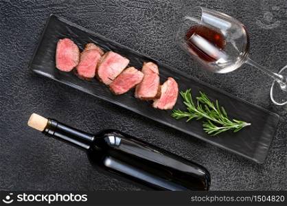 Bottle of red wine with sliced filet mignon: top view