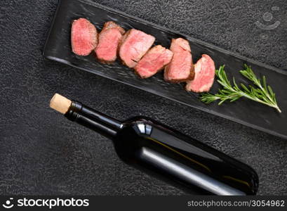 Bottle of red wine with sliced filet mignon: top view