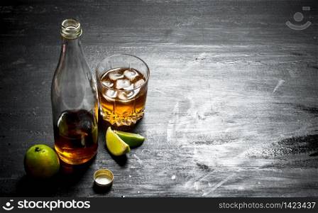 bottle of rum with lime. On a black wooden background.. bottle of rum with lime.