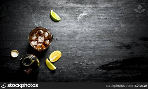 bottle of rum with lime. On a black wooden background.. bottle of rum with lime.