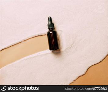 Bottle of serum oil cosmetic product on beach sand background. Abstract podium from natural materials product presentation on a sandy background. Top view copy space. Bottle of serum oil cosmetic product beach sand background. Abstract podium product presentation
