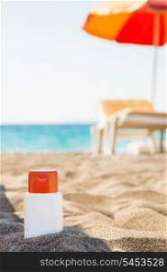 Bottle of sun block creme in shadow on beach