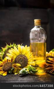 bottle of Sunflower oil with fresh blooming on dark wooden background