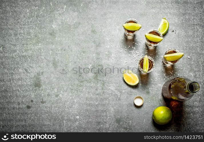 bottle of tequila with lime and salt. On the stone table.. bottle of tequila with lime and salt.