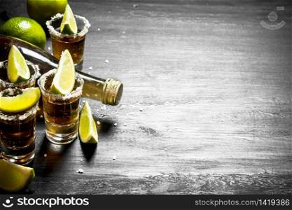 bottle of tequila with shot glasses, fresh lime and salt. On the chalkboard.. bottle of tequila with shot glasses, fresh lime and salt.