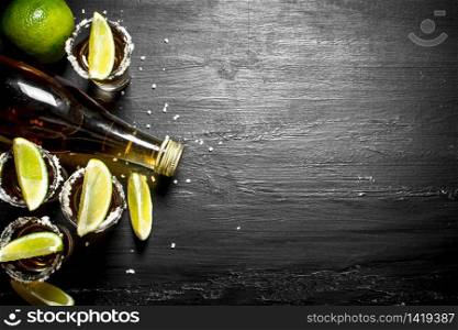 bottle of tequila with shot glasses, fresh lime and salt. On the chalkboard.. bottle of tequila with shot glasses, fresh lime and salt.