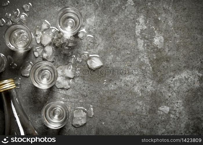 bottle of vodka with glasses and ice. On the stone table.. bottle of vodka with glasses and ice.