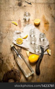 Bottle of vodka with shot glasses and lemon. On wooden background.. Bottle of vodka with shot glasses and lemon.
