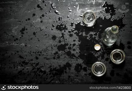 Bottle of vodka with shot glasses. On a black wooden background.. Bottle of vodka with shot glasses.