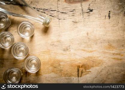 bottle of vodka with shot glasses. On wooden background.. bottle of vodka with shot glasses.