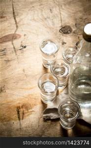 bottle of vodka with shot glasses. On wooden background.. bottle of vodka with shot glasses.
