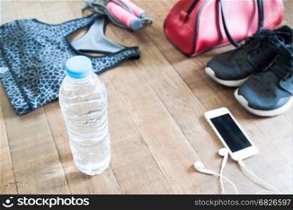 Bottle of water with mobile device and sport equipments on wood floor, Healthy lifestyle concept