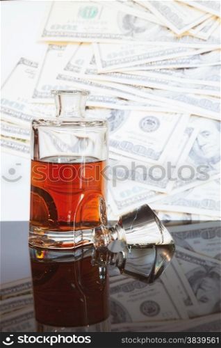 bottle of whiskey in the background of many hundred dollars