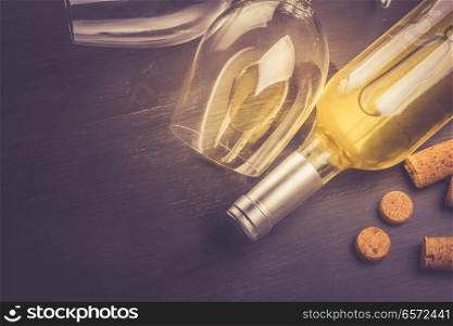 Bottle of white wine, corks and two wine glasse laying on table, top view toned image. Glass of red wine