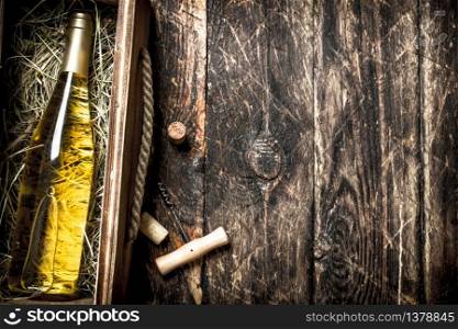 bottle of white wine in an old box. On a wooden background.. bottle of white wine in an old box.