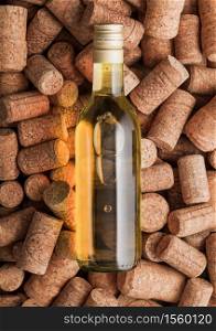 Bottle of white wine on top of various wine corks background. Macro