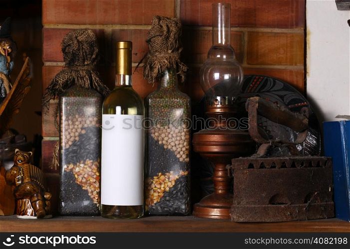Bottle of white wine with a blank label template standing on a fireplace shelf with various vintage objects