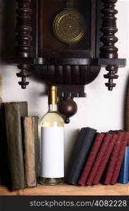 Bottle of white wine with blank label template standing on a shelf with books under an old clock