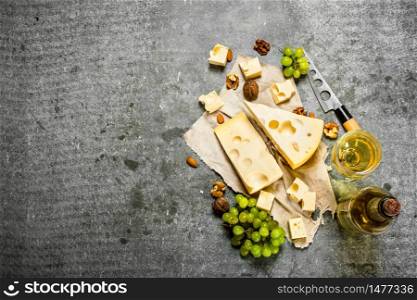 bottle of white wine with slices of fragrant cheese. On the stone table.. bottle white wine with slices of cheese.