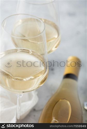 Bottle of white wine with two crystal glasses and steel corkscrew on light table background. Top view.Macro