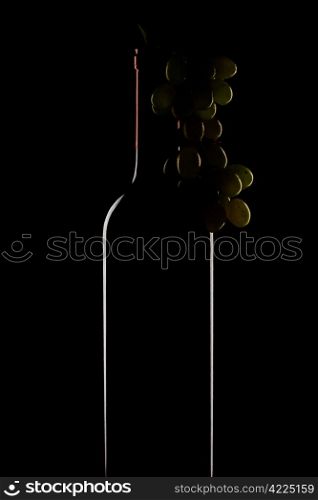 bottle of wine and a bunch of grapes on a black background