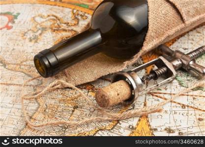 bottle of wine and a corkscrew on the background of old maps