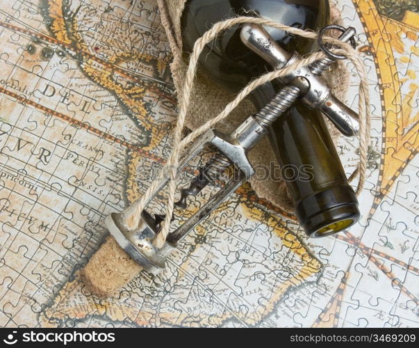 bottle of wine and a corkscrew on the background of old maps