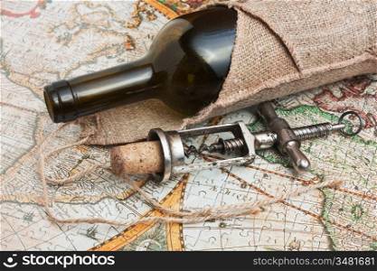 bottle of wine and a corkscrew on the background of old maps
