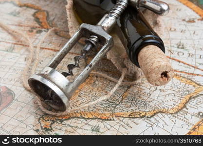 bottle of wine and a corkscrew on the background of old maps