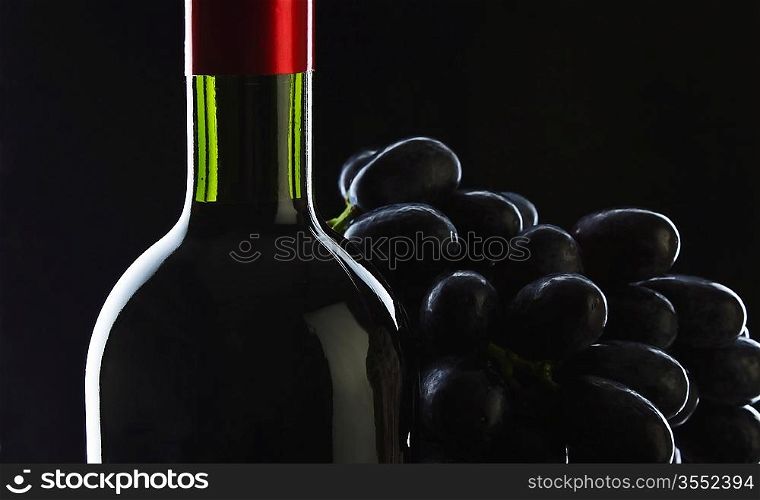bottle of wine and grapes on black background