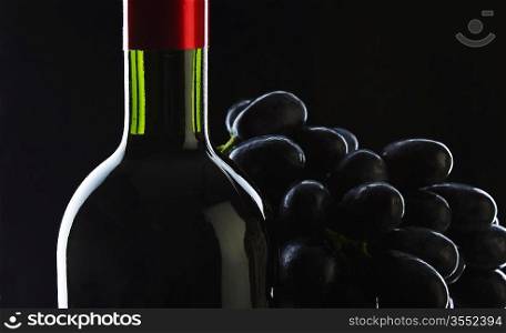 bottle of wine and grapes on black background