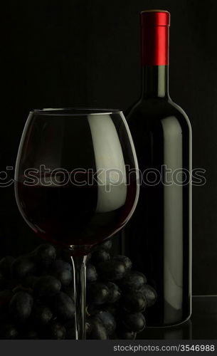 bottle of wine and grapes on dark background