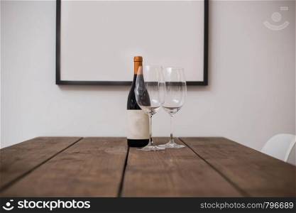 bottle of wine and two glasses on a wooden table in a modern home. bottle of wine and two glasses on a wooden table