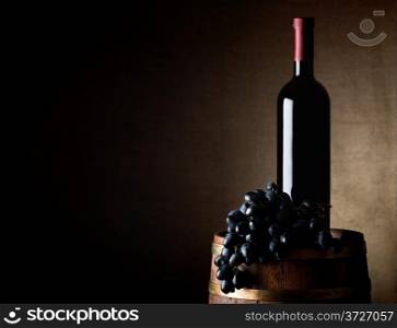Bottle of wine with grape on an old wooden barrel