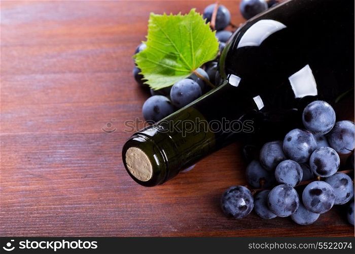 bottle of wine with grape on wooden table