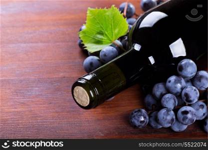 bottle of wine with grape on wooden table