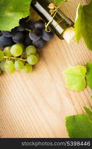 bottle of wine with leaves and grapes on wooden table