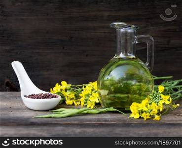 bottle rapeseed oil seeds and flowers on rustic wooden background. canola oil, flowers and seeds on rustic wood