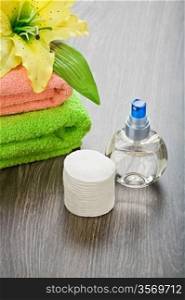 bottle towels flower and cotton pads on wooden background