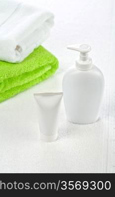 Bottle tube and towels on white background