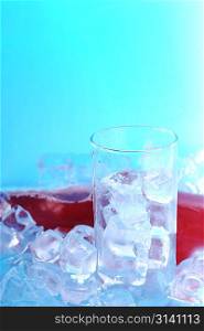 bottle with drink and glass with ice on surface