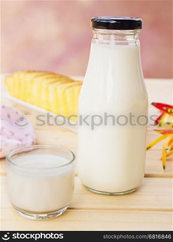 Bottle with glass of milk and butter cake on white wooden table.