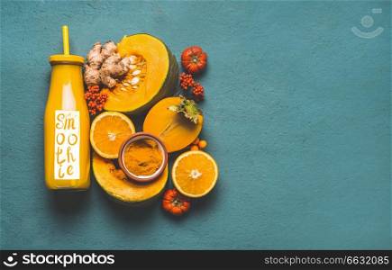 Bottle with healthy energetic drink and word smoothie, for cold season with orange ingredients   pumpkin, persimmon , orange fruits, ginger and turmeric or curcuma powder , top view