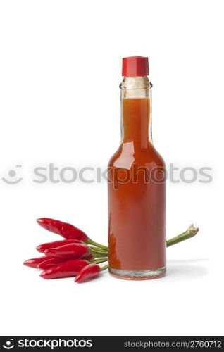 Bottle with hot chili pepper sauce and fresh tabasco peppers on white background