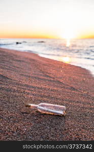 Bottle with message inside on the shore at the beach