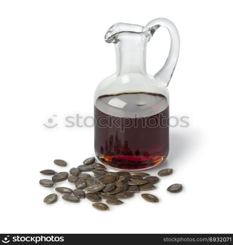 Bottle with pumpkin seed oil and roasted seeds on white background