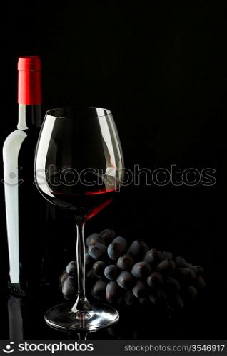 bottle with red wine and glass and grapes