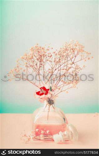 Bottle with room fragrance and flowers on pastel background, front view